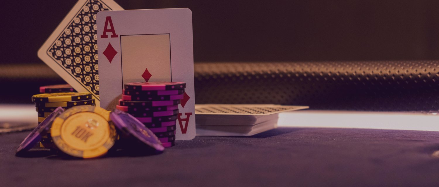A diamond ace propped against violet and gold poker chips on a dark felt table — the visible surface of a club game whose fairness is decided off the table.